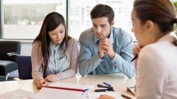 A couple review their insurance coverage while sitting at a desk with an agent.